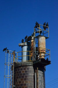 Low angle view of factory against clear blue sky