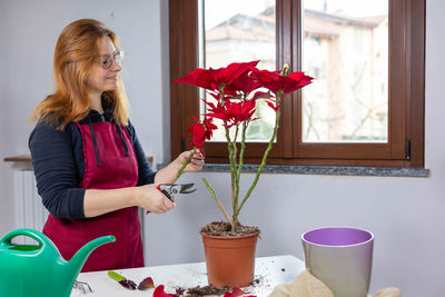Young woman holding potted plant at home