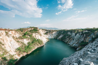 Panoramic shot of water flowing through rocks against sky