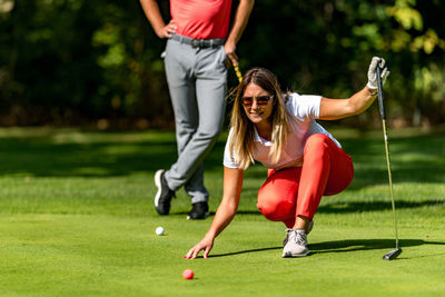 Couple playing golf, young woman reading green, getting ready to putt