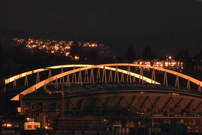 Illuminated bridge over river in city at night