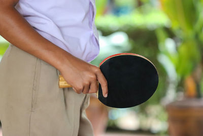 Midsection of boy holding table tennis racket while standing outdoors