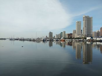 Sailboats in city by buildings against sky