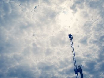 Low angle view of crane against cloudy sky