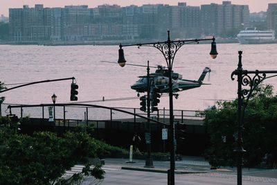 Helicopter over street against river