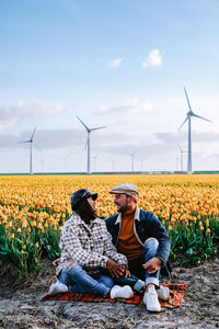 Men sitting on field against sky