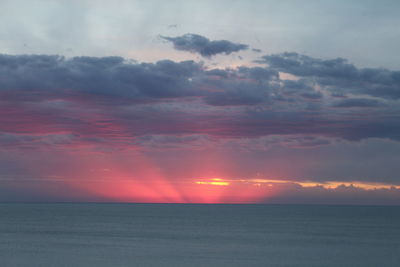 Scenic view of sea against dramatic sky during sunset