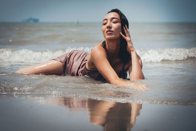 Beautiful young woman on beach against sky
