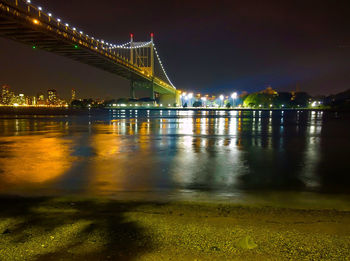 Illuminated bridge over river against sky at night