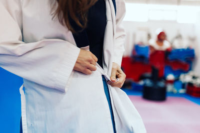 Midsection of man holding woman standing against white wall