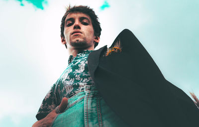 Portrait of young man looking away against sky