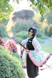 Side view of young woman standing against trees