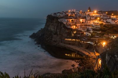 High angle view of illuminated buildings by sea