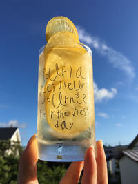 Close-up of hand holding drink against sky