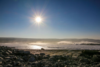 Scenic view of sea against bright sun