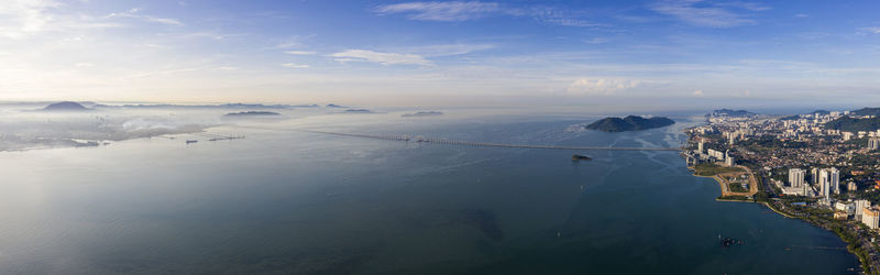 Aerial view of city by sea against sky