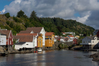 Houses by river and buildings against sky