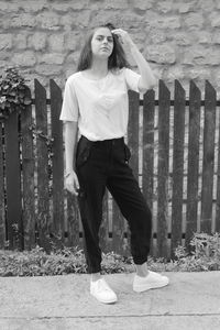 Portrait of young woman standing against brick wall