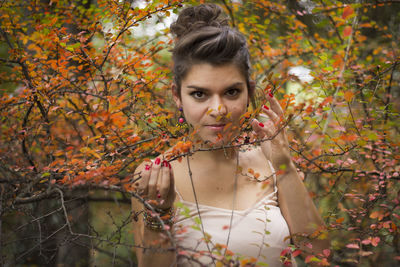 Portrait of young woman standing in autumn leaves