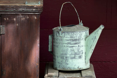 Close-up of old watering can on stool