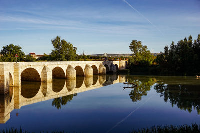 Arch bridge over river against sky