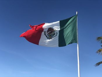 Low angle view of flag against clear blue sky