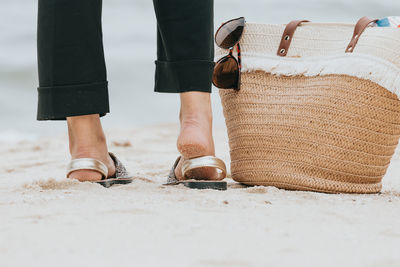 Low section of man standing on sand at beach