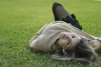 High angle portrait of young woman lying on grassy field