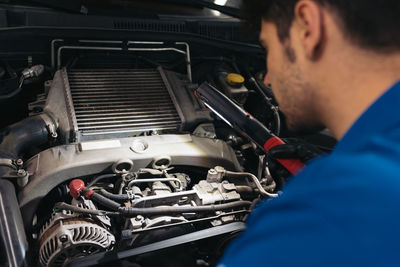 Close-up of mechanic examining car in garage