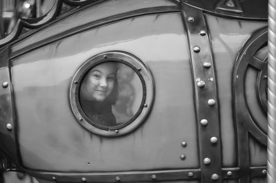 Portrait of girl peeking through window of outdoor play equipment