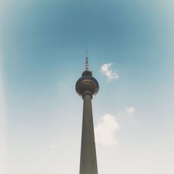 Low angle view of communications tower and building against sky