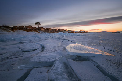 Scenic view of snow covered land against sky during sunset