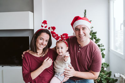 Baby girl with parents at home during christmas