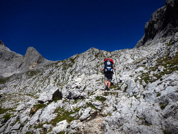 Male backpacker climbing on mountain against sky