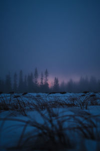 Snow covered landscape against sky during sunset