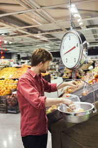 Man weighing apples at supermarket