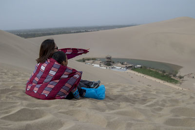 Rear view of woman on beach against sky