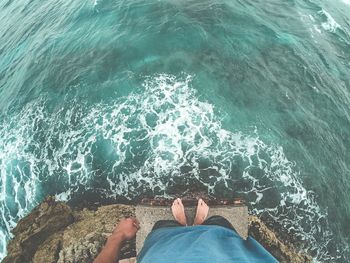 Low section of person on rock by sea
