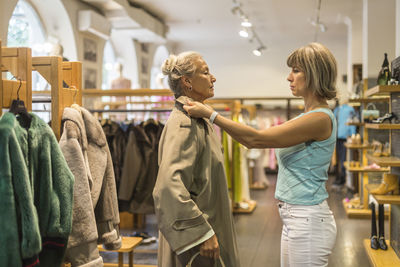 Senior woman trying on coat in a boutique