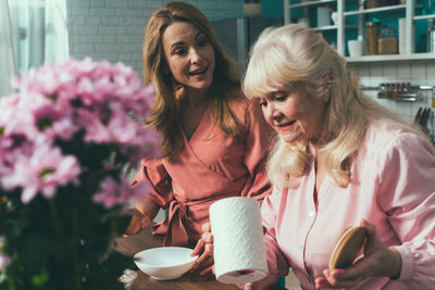 Cheerful daughter and mother preparing muffins at kitchen