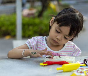 Close-up of cute girl playing with childs play clay at table outdoors