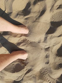 Low section of woman standing on sand