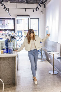 Full length portrait of woman standing at home