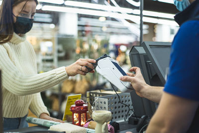 Young woman checks out using the phone through the terminal in the store. social distancing.