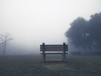Empty bench on field against sky during winters
