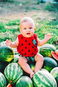 Portrait of cute baby boy sitting over watermelons