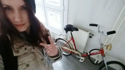 Portrait of woman with bicycle standing at home