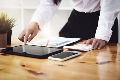 Midsection of man using mobile phone on table