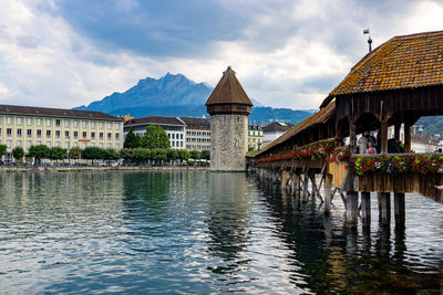 Bridge over river by buildings against sky