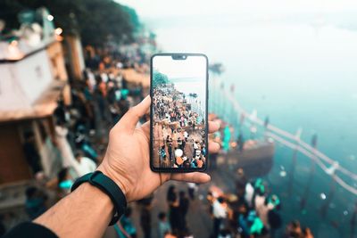 Midsection of person holding mobile phone in city